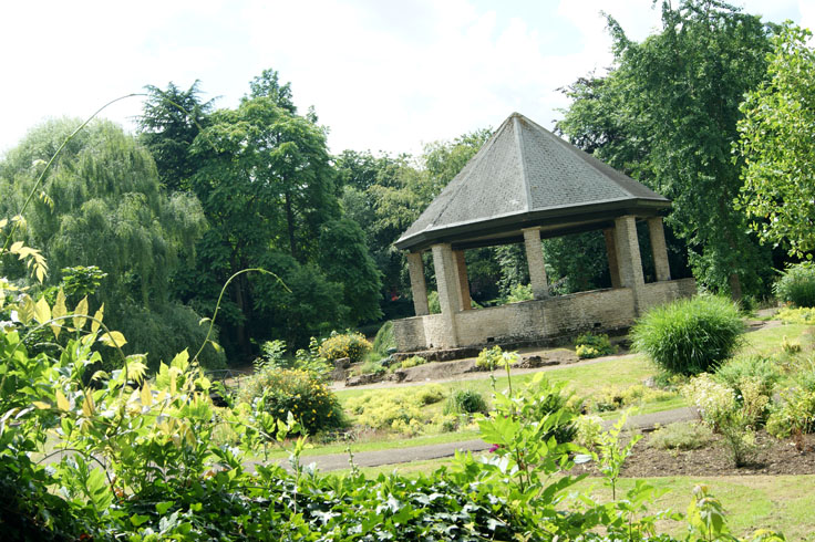 A park garden with a bandstand in the middle.